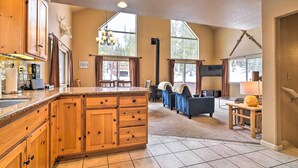 A spacious kitchen with wooden cabinets, a large island, and a dining area with a blue sofa and table. - Great for Groups: Soda Springs Cabin w/ Deck! (Soda Springs)