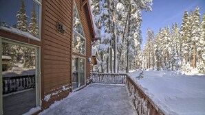 A wooden cabin with a snow-covered balcony and surrounding snow-laden trees. - Great for Groups: Soda Springs Cabin w/ Deck! (Soda Springs)