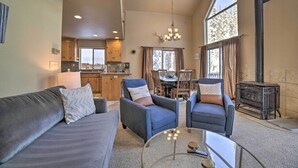 A spacious living area with a sofa, armchairs, and a coffee table. A kitchen is visible in the background, and a fireplace is present. - Great for Groups: Soda Springs Cabin w/ Deck! (Soda Springs)