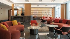 A modern lobby with red sofas, a coffee bar, and a fireplace. - Nujiang Hotel (Lushui)