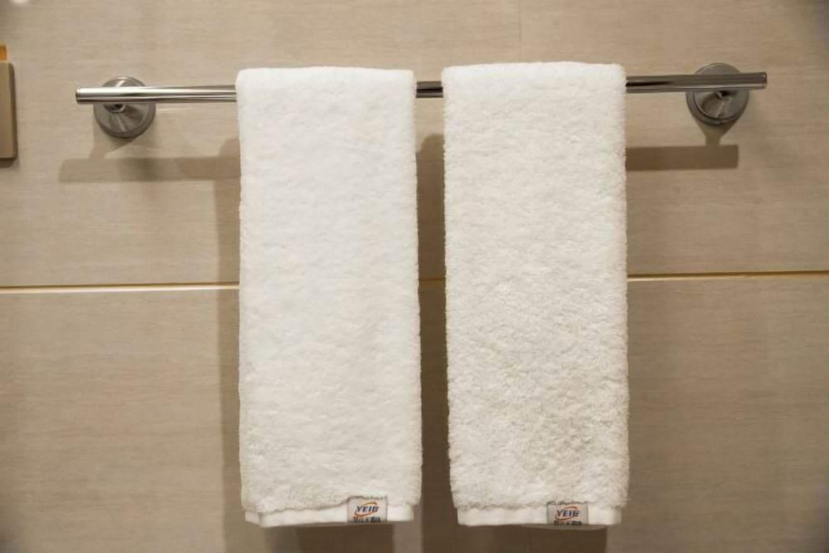 Dos toallas blancas colgadas en un perchero metálico en un baño.
