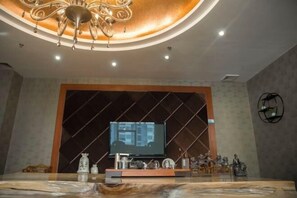 Una sala de estar moderna con un televisor de pantalla plana grande montado en una pared oscura, una lámpara decorativa en el techo y una mesa de centro de mármol.