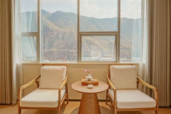 Enjoy breathtaking views of the surrounding mountains from the comfort of this room, featuring a large window and stylish seating area.