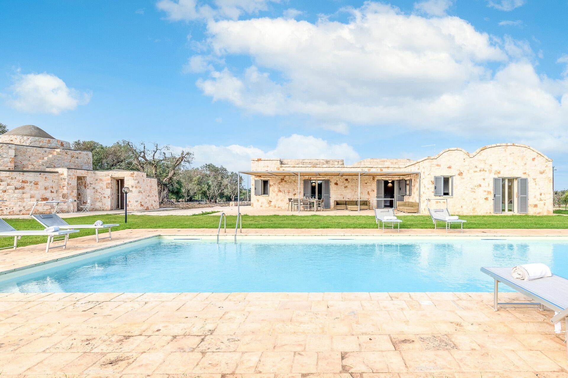 A pool area with lounge chairs and a building with stone walls and a dome structure.