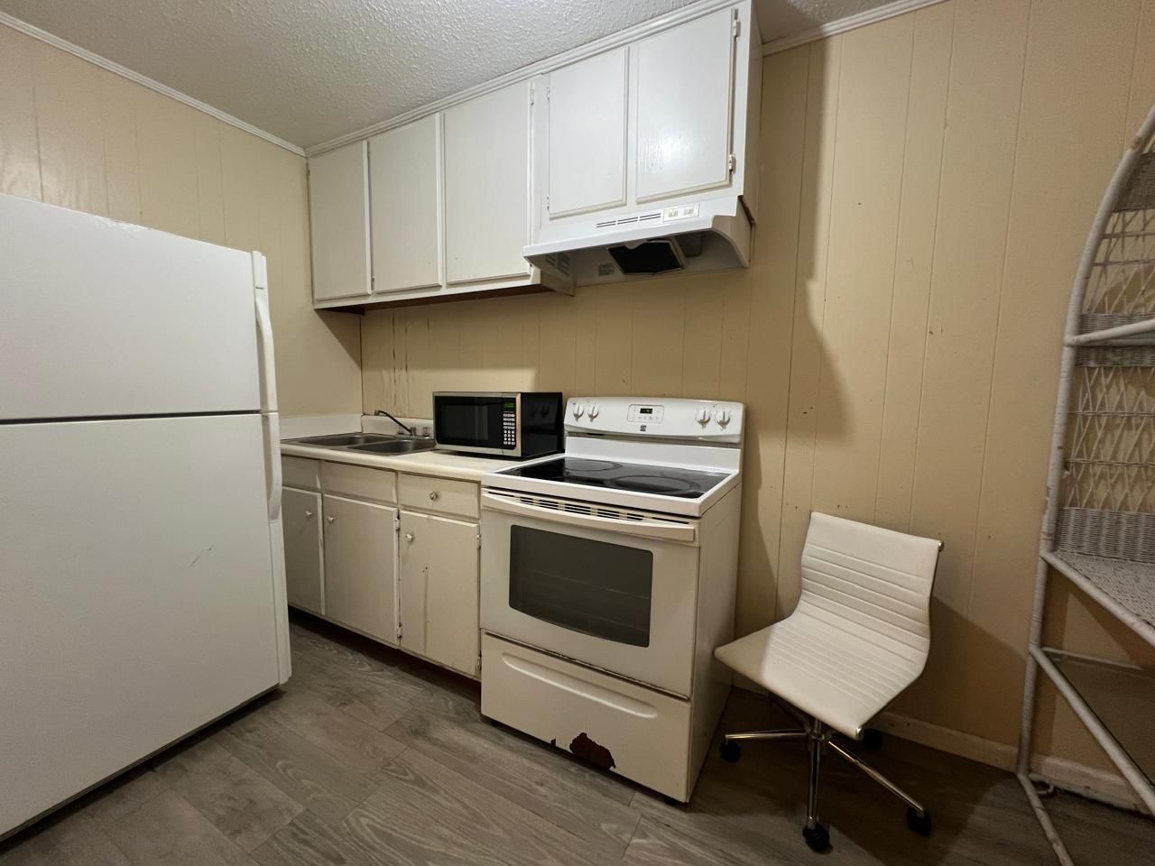 Una cocina compacta con electrodomésticos blancos, incluyendo un refrigerador, microondas y estufa.