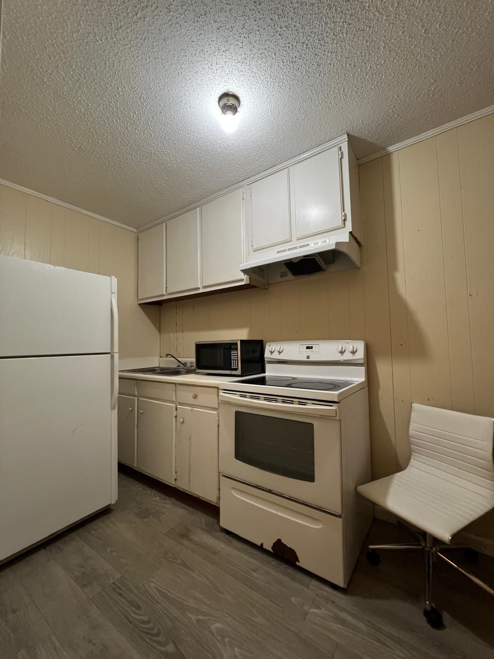 A compact kitchen with a refrigerator, microwave, stove, and oven.