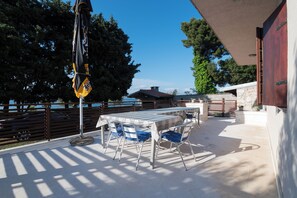 Eine Terrass mit Tisch und Stühlen, ein Metallzaun und ein Gebäude mit einer Steinmauer.