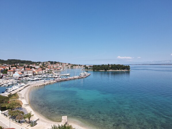A coastal town with a marina, clear blue waters, and a sandy beach.