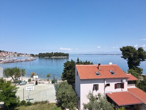 Blick auf die Küste mit einem Yachthafen, einem weißen Gebäude mit rotem Dach und blauem Himmel.