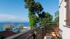 Ein Balkon mit Meerblick, ein Holzstuhl und ein Gebäude mit weißer Fassade.