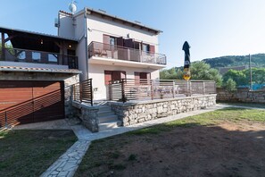 A two-story building with a stone staircase, a balcony, and a flag.