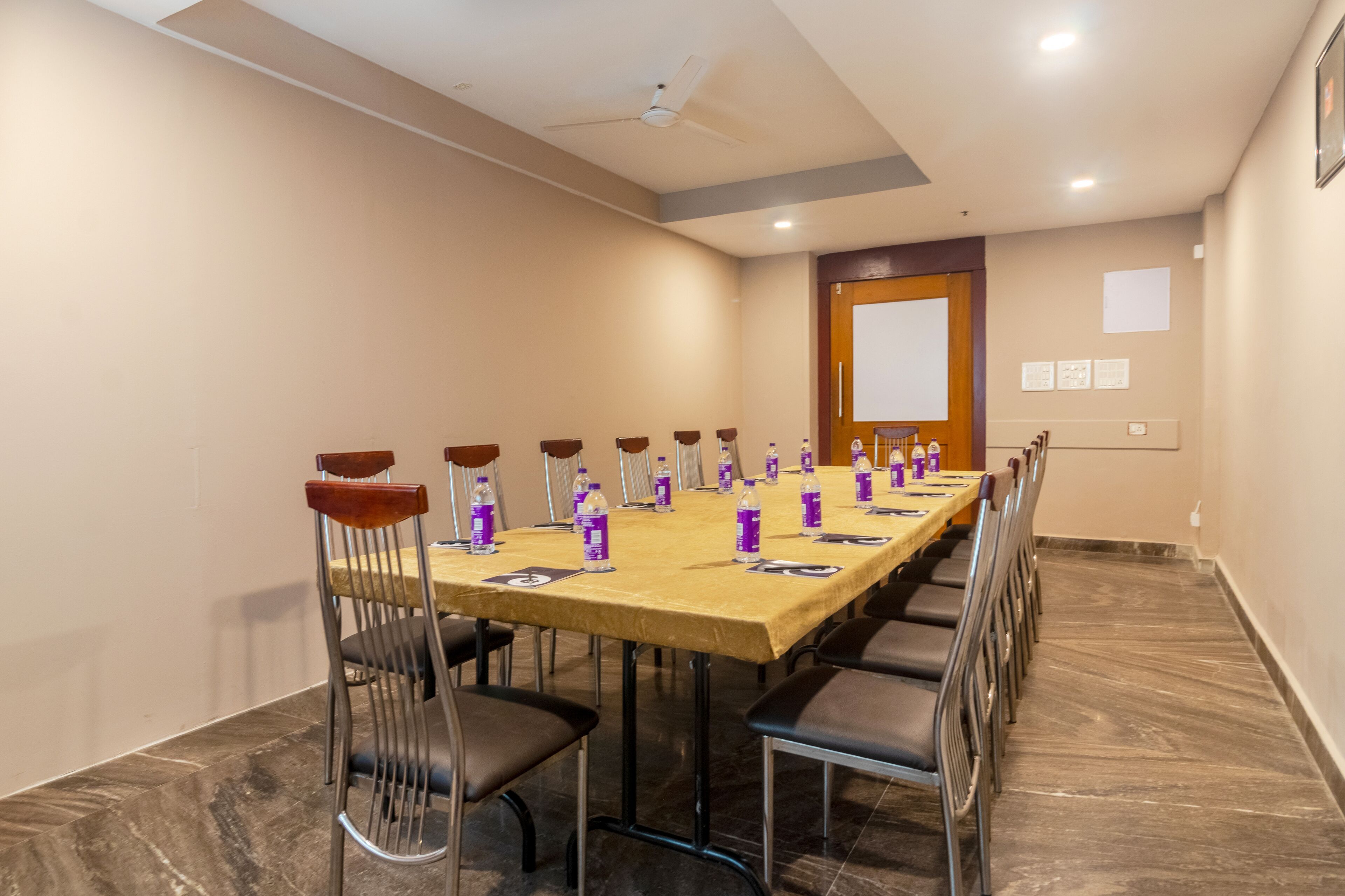 Un salón de conferencias con una larga mesa, sillas y botellas de agua.