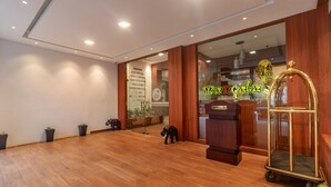 A spacious lobby with wooden flooring, a reception desk, a large mirror, and a decorative elephant statue.