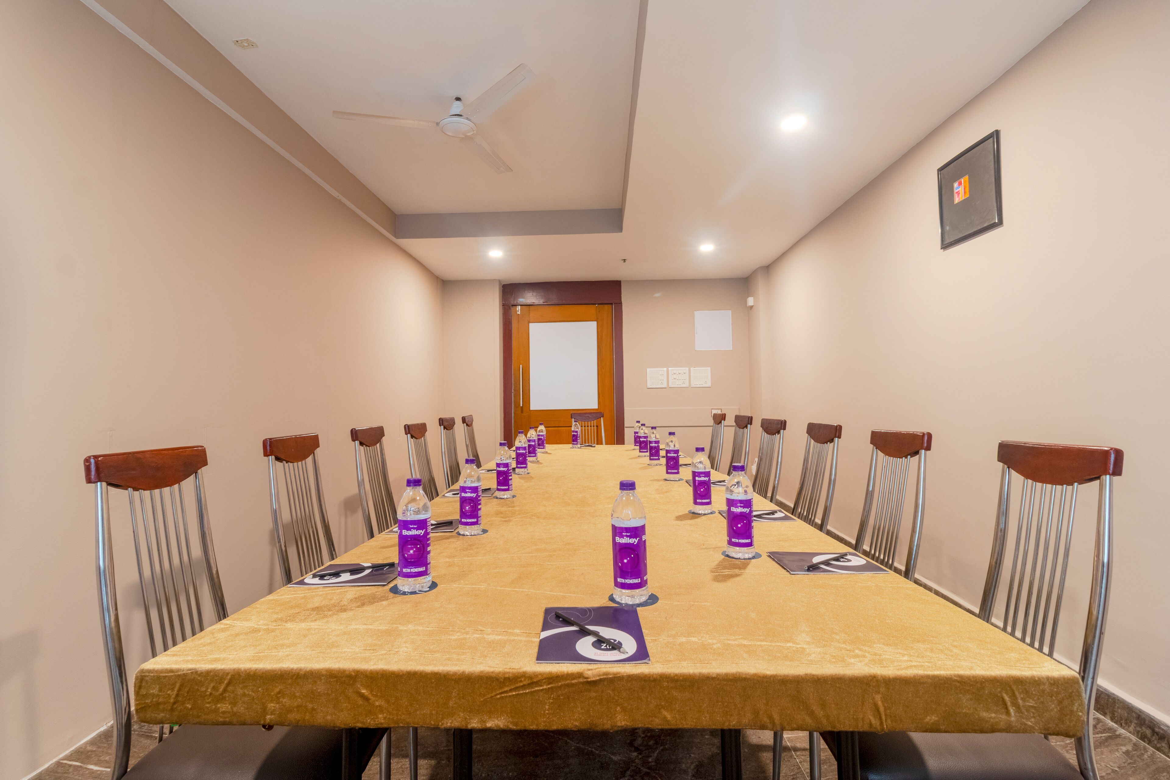 Un salón de conferencias con una larga mesa, sillas y botellas de agua.