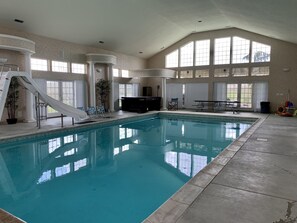 An indoor swimming pool with a slide, seating area, and large windows. - Mapleway Manor, Indoor Pool, Jacuzzi, Sauna & Theatre Room (Selah)