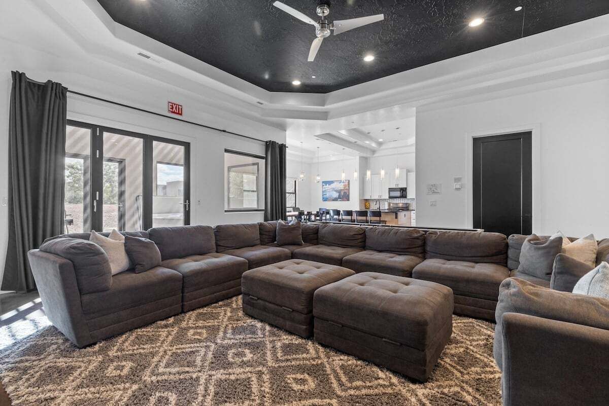 A spacious living area with a large sectional sofa, a ceiling fan, and a patterned rug.