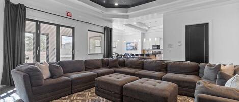 A spacious living area with a large sectional sofa, a ceiling fan, and a patterned rug.