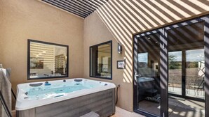 Ein moderner Außenbereich mit Whirlpool, einer Holzbank, großen Fenstern und einer Pergola-Struktur.