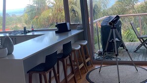 A modern kitchen with a large island, bar stools, and a view of the outdoors. - Immaculate designer house-sweeping views over iconic Blueys Beach 3min walk away (Blueys Beach)