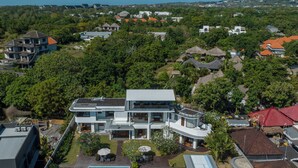 A modern two-story house with a swimming pool, surrounded by lush greenery and a hilly landscape. - Villa Balangan Sunset (Jimbaran)