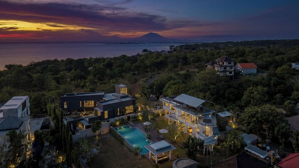 A modern house with a swimming pool, surrounded by lush greenery and a view of the sea at sunset. - Villa Balangan Sunset (Jimbaran)