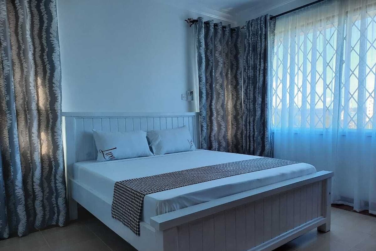 A bedroom with a bed, curtains, and a window.