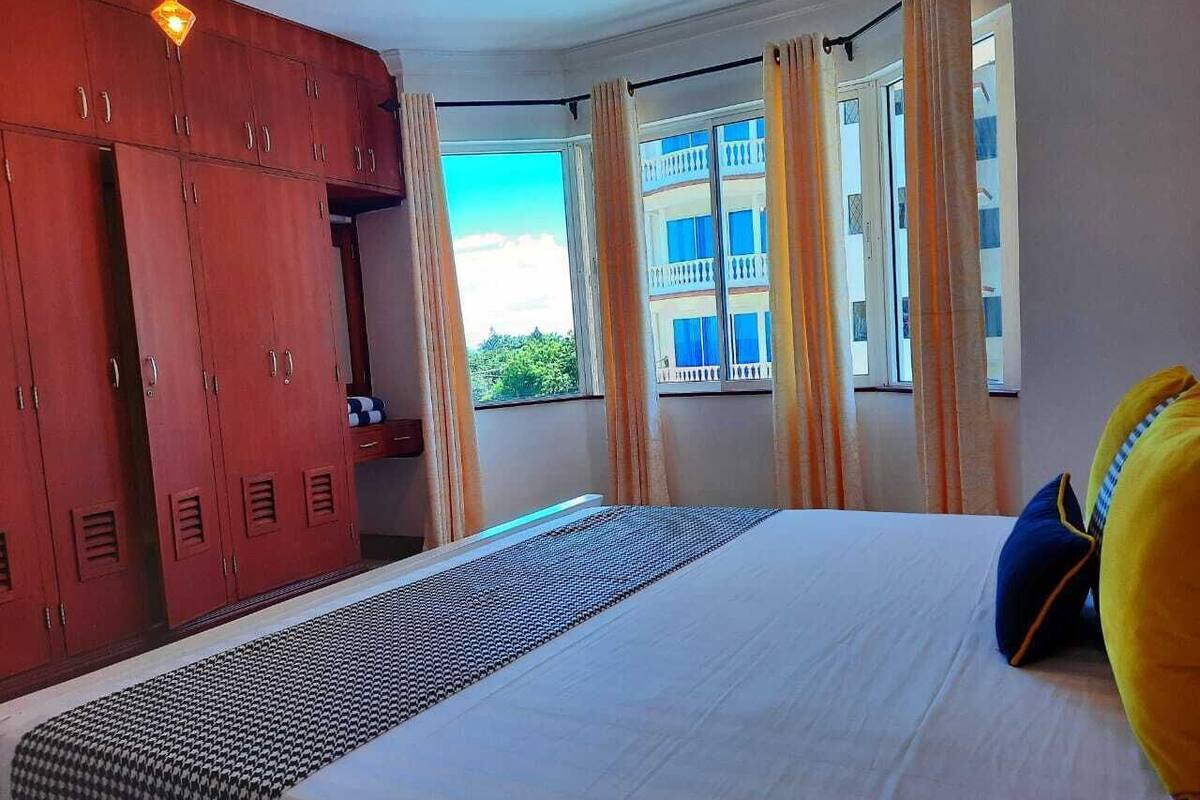 A hotel room with a bed, a wardrobe, and a window with curtains.