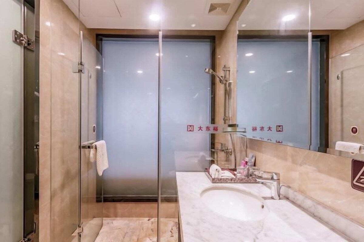 A modern bathroom with a glass shower enclosure, a marble sink, and a large mirror.