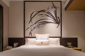 A neatly made bed with white linens and pillows, a wall-mounted artwork of abstract floral design, and bedside tables with lamps and a phone. - Da Dong Yu Hotel (Zhongshan)