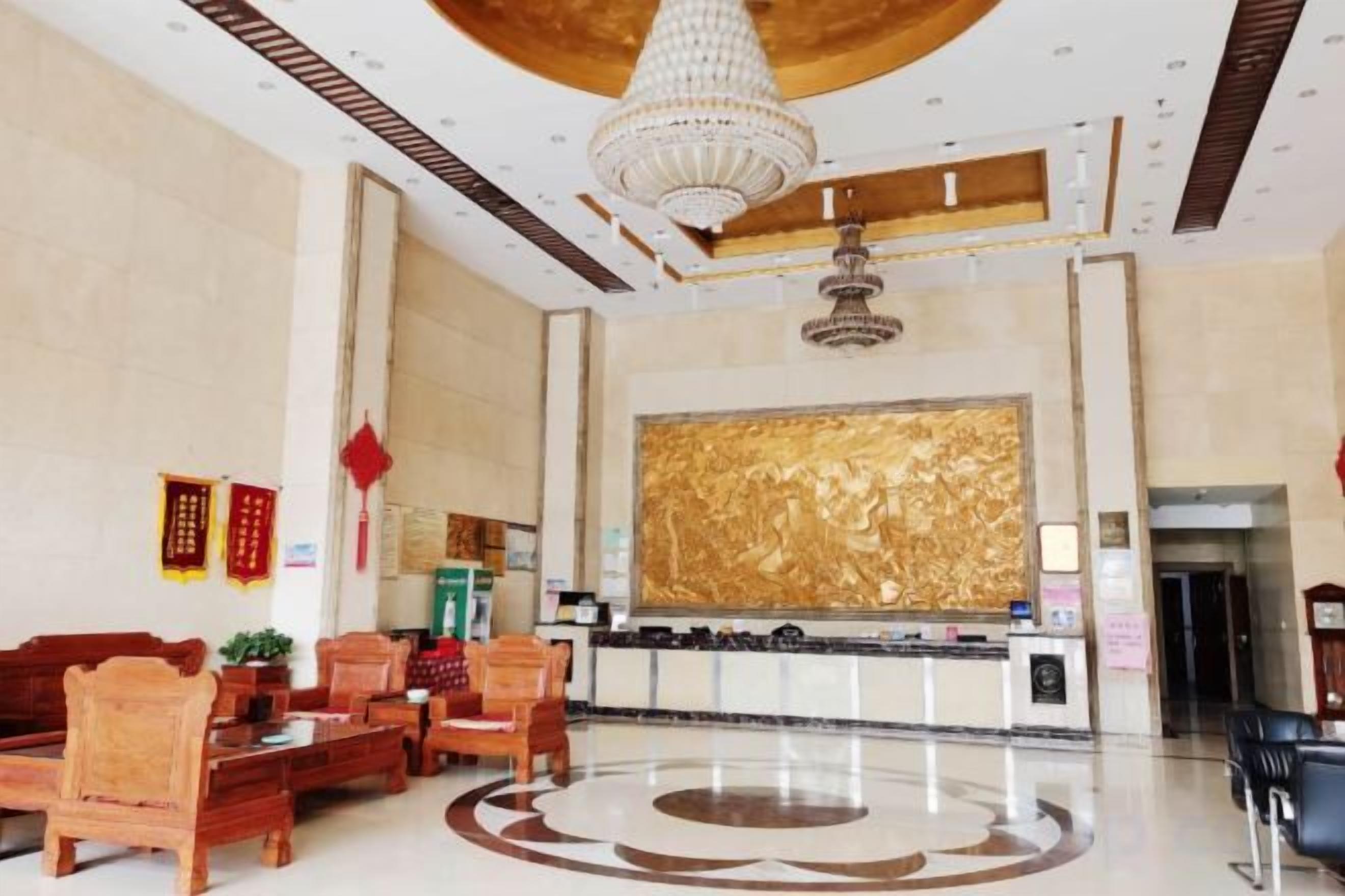 A hotel lobby with a reception desk, seating area, and a large decorative wall.