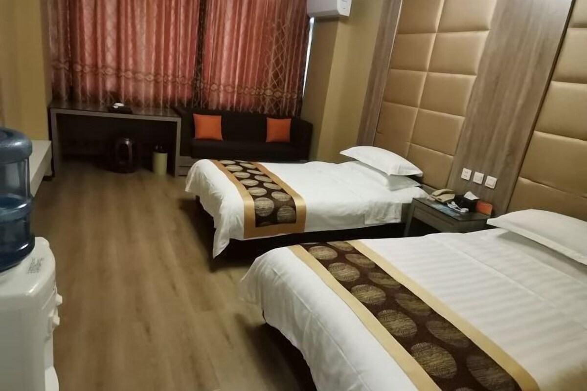 A hotel room with two beds, a desk, and a water dispenser.