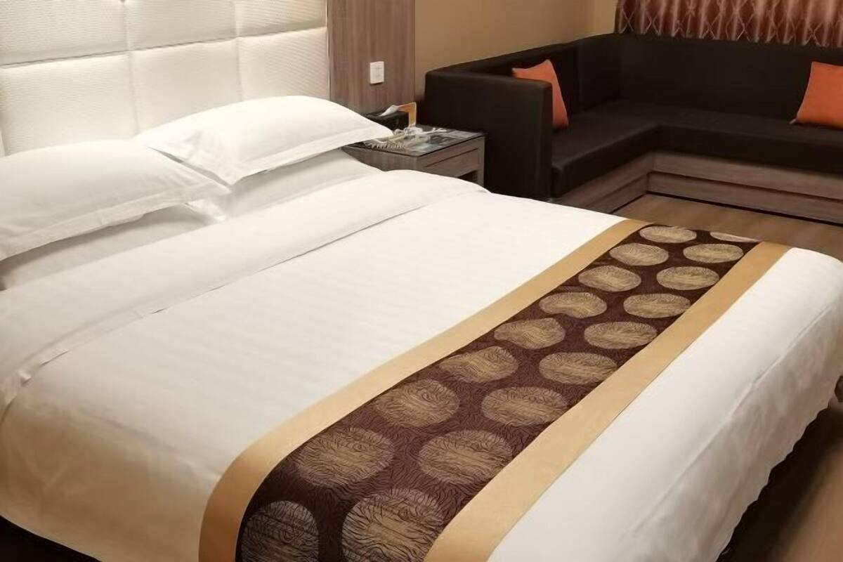 A neatly made bed with white linens and a patterned throw blanket.