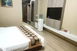A hotel room with a bed, a water dispenser, a TV, and a small shelf with toiletries. - Fuhua Hotel (Shouguang)