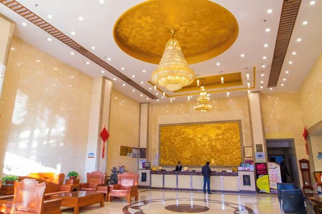 A hotel lobby with a reception desk, seating area, and a chandelier.