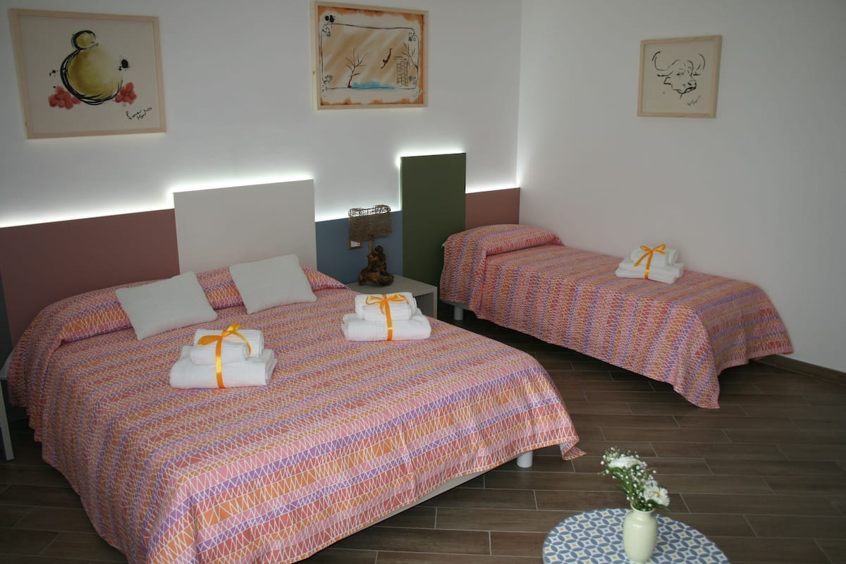 Habitació d'hotel amb dos llits, cadascun amb un estriat i tovalloles. Hi ha aplics de paret, una petita estàtua i quadres a les parets.