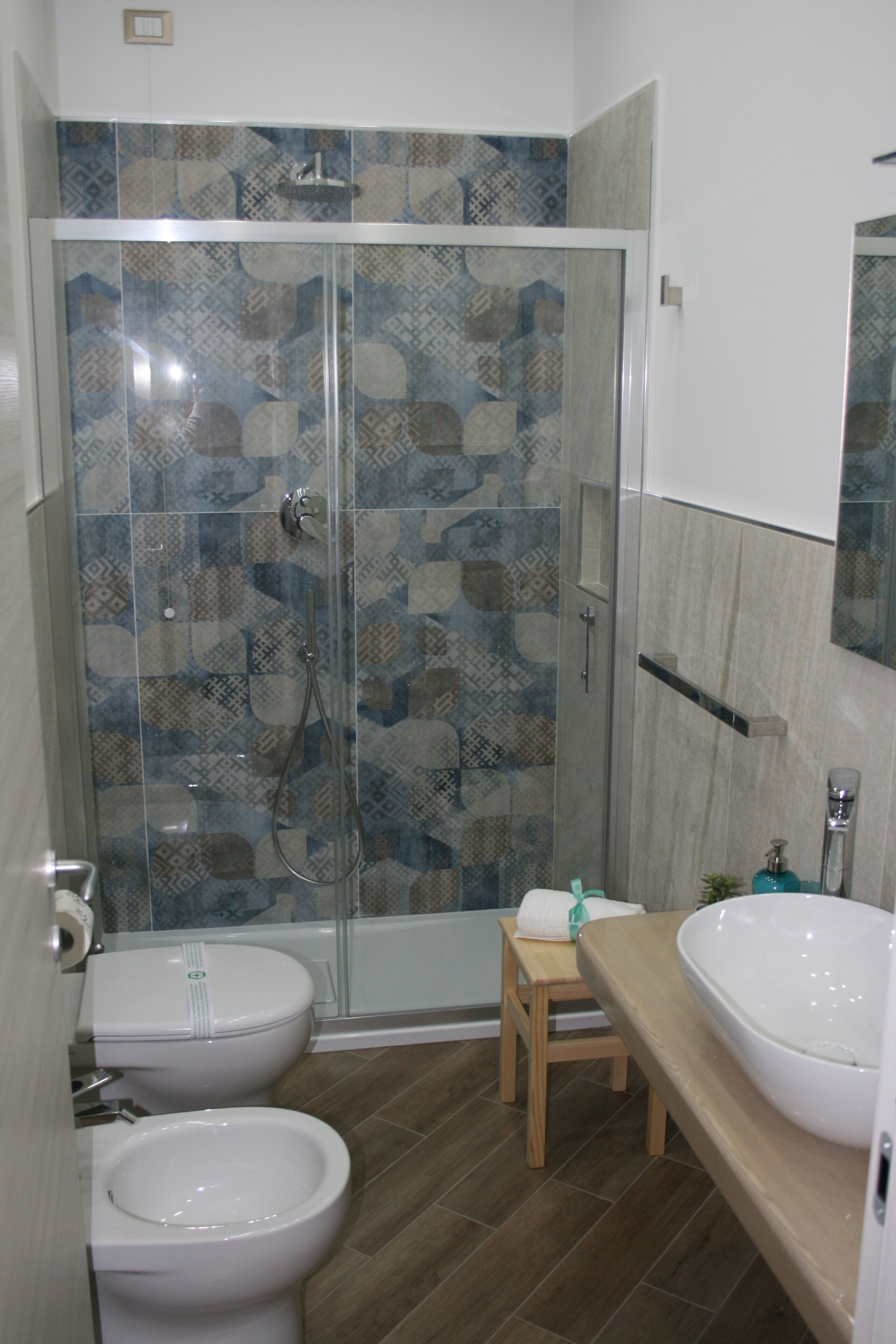 A bathroom with a shower enclosure, a toilet, a bidet, and a sink.