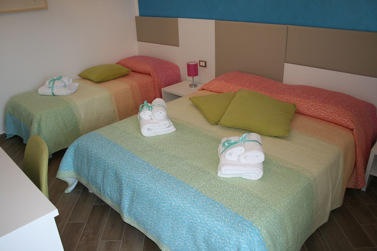 Dos llits individuals amb tovelloles, una tauleta de nit i una làmpada a una habitació d'hotel.