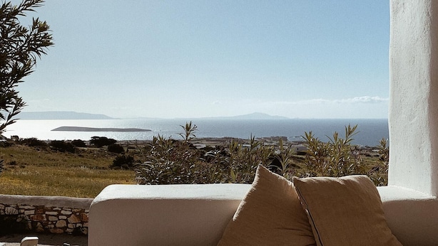 A cozy outdoor seating area with a view of the sea and distant mountains. - Maisonette with breathtaking views of the Cyclades (Aspro Chorio)