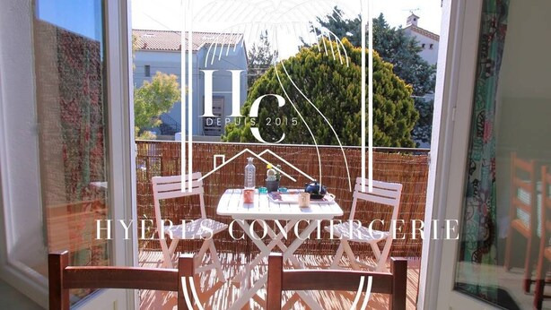 A sunlit patio with a table and chairs, a wicker basket, and a view of a building through a glass door.