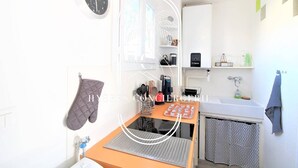 A compact kitchen with a clock, a coffee machine, and a sink.