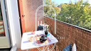 A balcony with a table set for two, a chair, and a decorative umbrella.