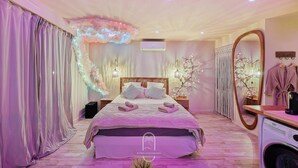 Ein Schlafzimmer mit einem großen Bett, einem Schminktisch mit Spiegel und einer Waschmaschine.