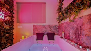 Ein modernes Badezimmer mit Marmorwand, einer Badewanne und zwei dunkel gefärbten Stühlen.