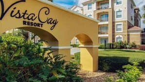 Une enseigne indiquant l’emplacement du Vista Cay Resort, avec un immeuble à plusieurs étages en arrière-plan.