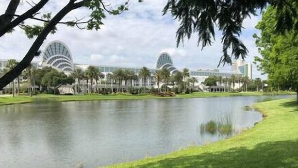 Un bâtiment moderne doté d’un toit incurvé et surplombant une vaste étendue d’eau.