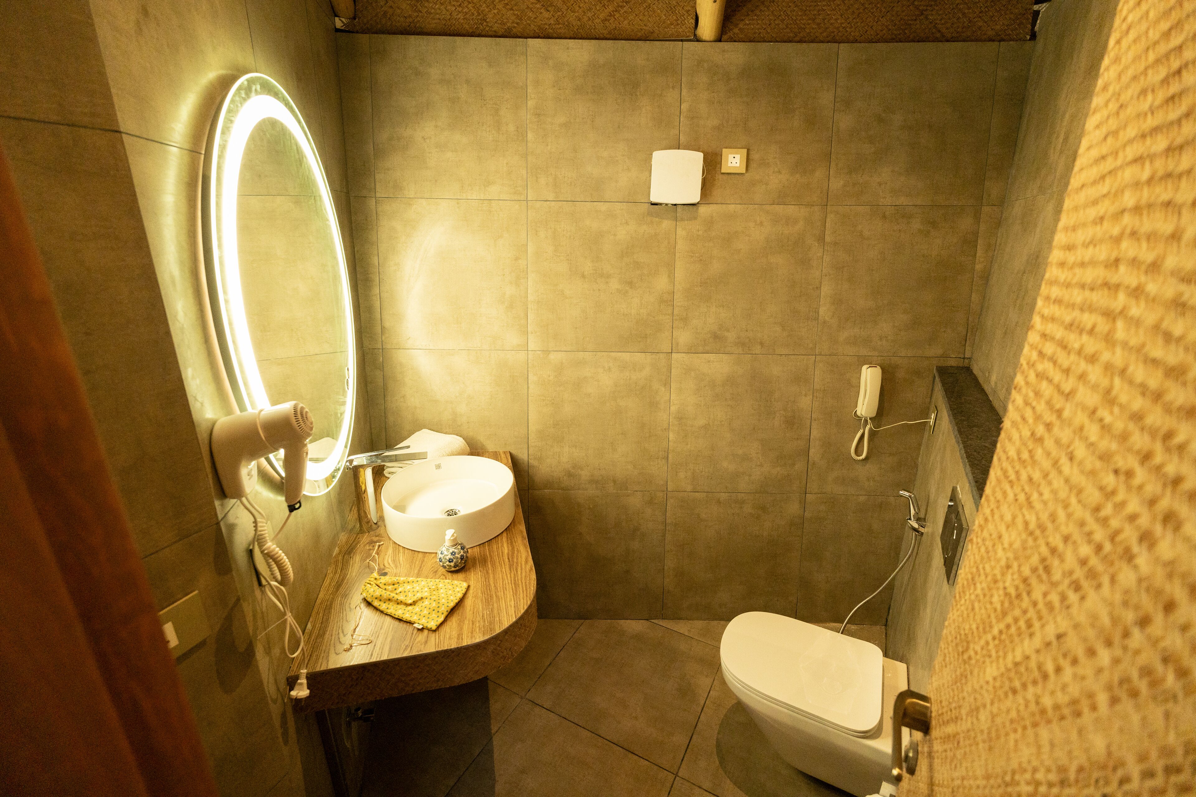 A bathroom with a round mirror, a sink, a toilet, and a towel rack.