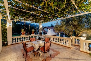 Eine Terrass mit sechseckigen Fliesen, einer weißen Pergola und Topfpflanzen.
