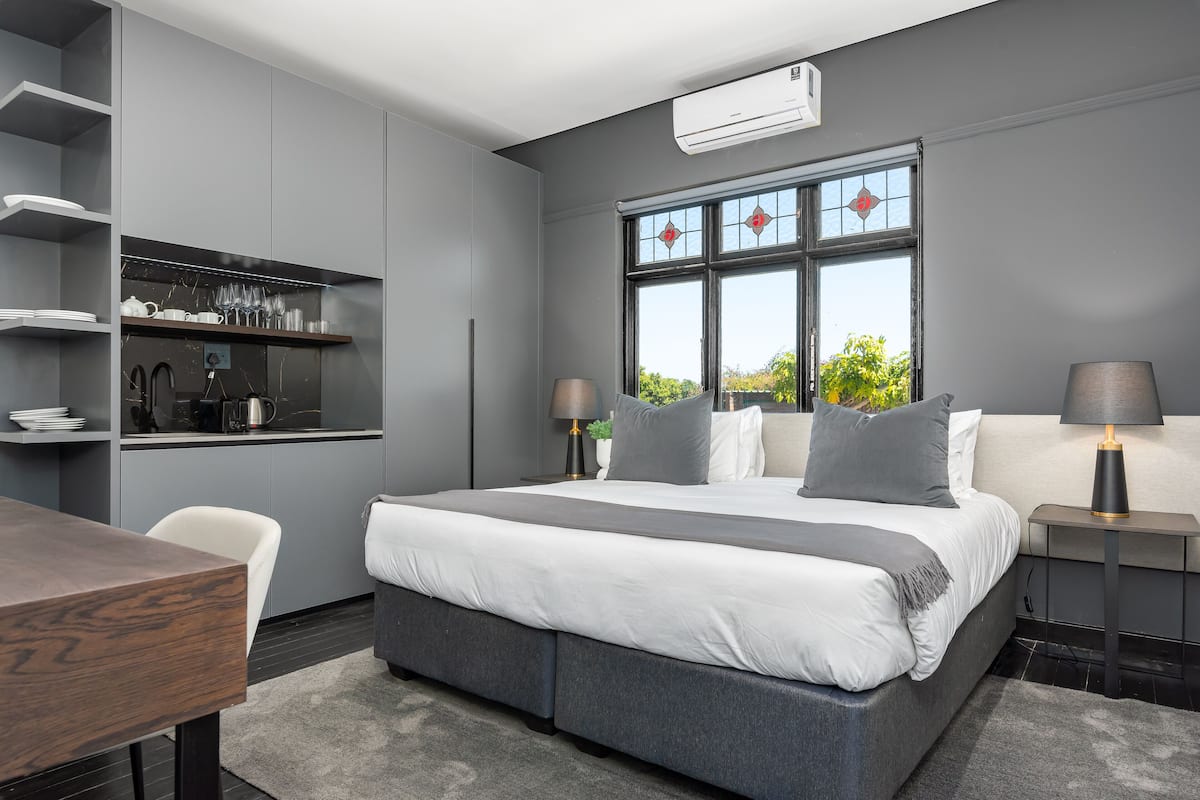 A modern bedroom with a large bed, bedside tables, a built-in wardrobe, and a window with a view.