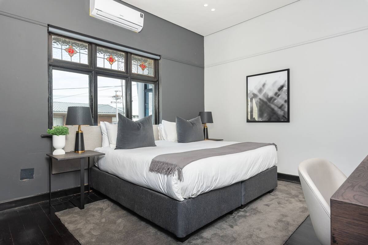 A modern bedroom with a large bed, bedside tables, a desk, and a chair.