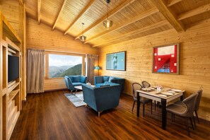 Estudi en suite de luxe, 1 llit de matrimoni gran, balcó, vistes a la muntanya | Sala d'estar | Televisor LED de 42 polzades amb canals per cable i llibres 